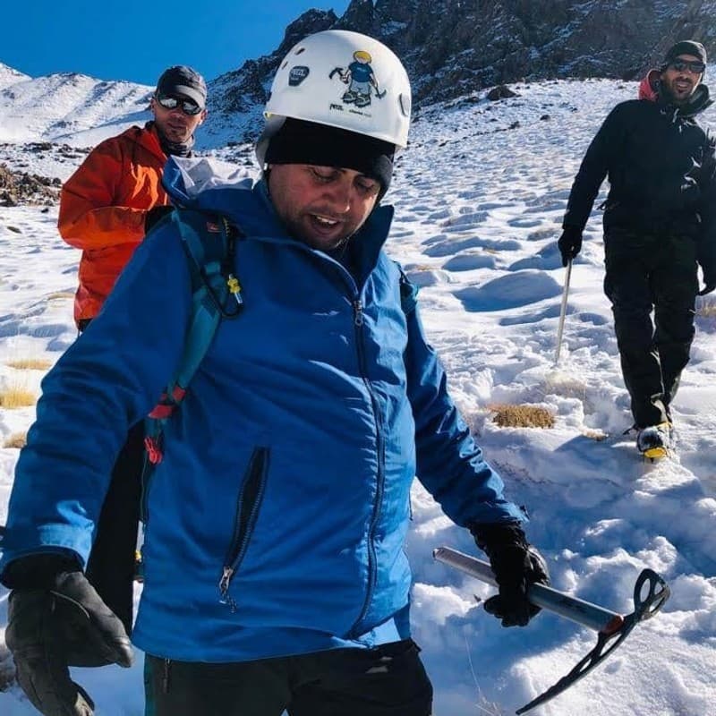 Aziz Mahmouch on a snow slope in the High Atlas in winter, wearing a climbing helmet and carrying an ice axe