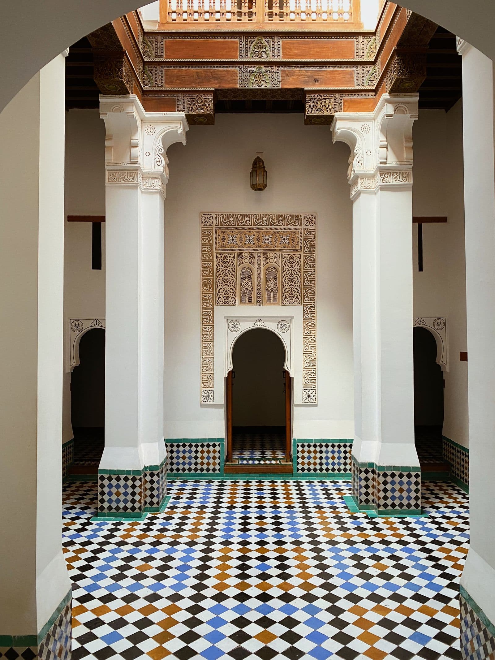 A Moroccan courtyard with zellij dado, carved stucco and a cedar-beamed gallery above