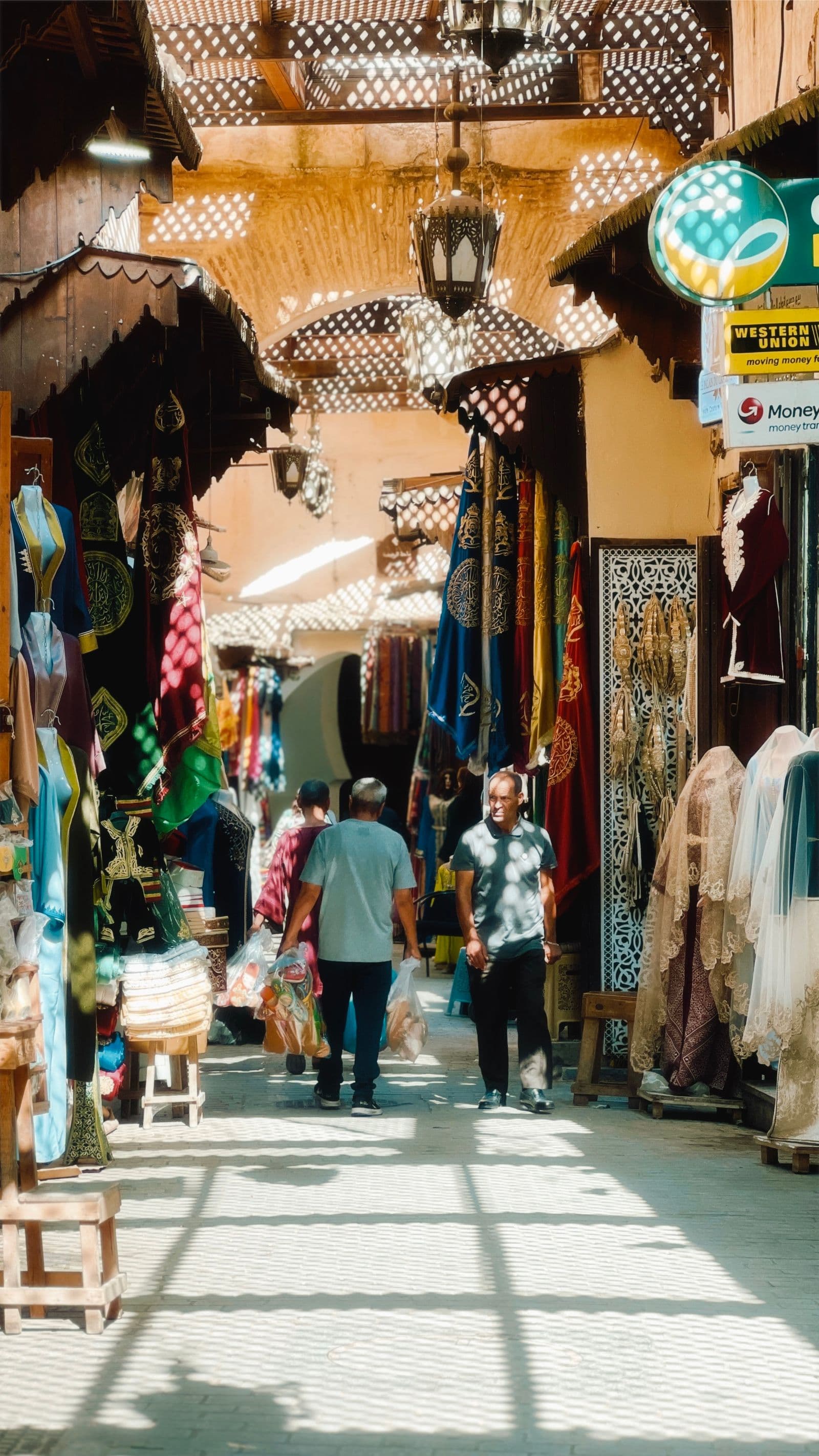 A narrow busy souk alleyway in Fez lined with stalls and hanging goods