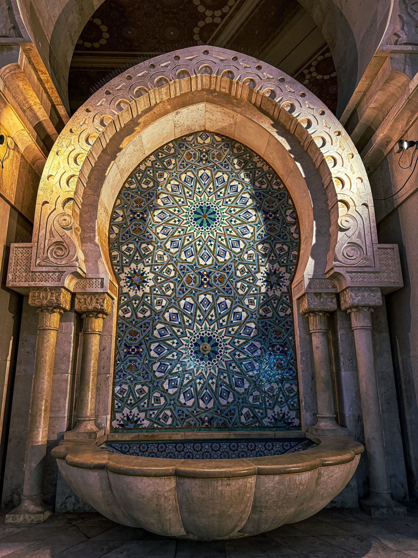 An intricate zellij mosaic panel framed by a traditional Moroccan arch, eight-pointed stars in glazed colour