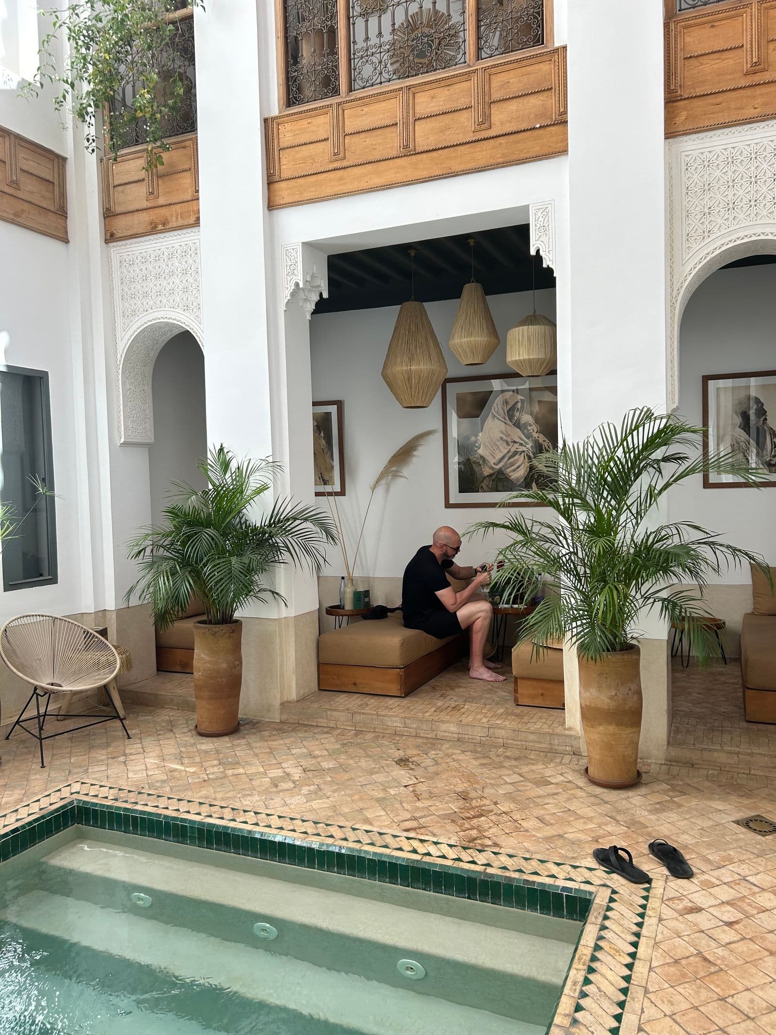 A calm riad courtyard with a small plunge pool, palms and shaded seating